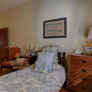 A cozy bedroom with a single bed, dresser, and wall art.