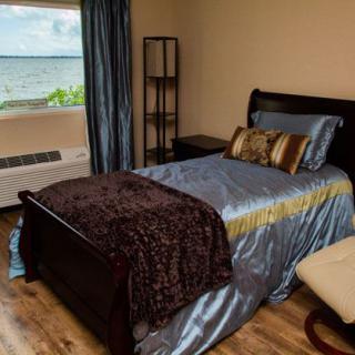 A cozy bedroom with a single bed and a scenic lake view through the window.