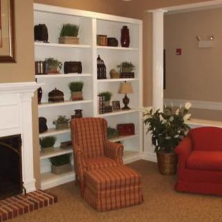 A cozy living room with a fireplace, bookshelves, and armchairs.