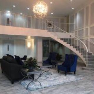 A modern and luxurious living room with elegant furniture, a chandelier, and a sweeping staircase.