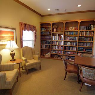 A cozy reading room with bookshelves, armchairs, and a table.