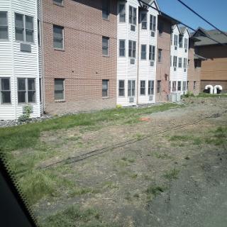 A view of residential buildings with a grassy area in the foreground.