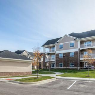 A modern suburban apartment complex with a parking lot and well-maintained surroundings.