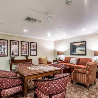 A cozy living room featuring a comfortable seating area with sofas and chairs, a central table, decorative artwork on the walls, and warm lighting.