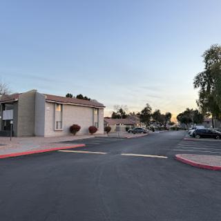 A peaceful evening scene in a residential neighborhood with buildings lining the street and a clear sky.