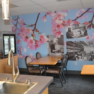 A cozy cafe interior featuring cherry blossom wall art and seating arrangements.