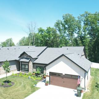 A suburban house with a front yard and garage, surrounded by trees.