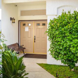 A welcoming house entrance with a bench and lush greenery.