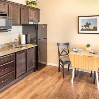 A cozy kitchen with dark wood cabinets, a small dining table, and modern appliances.