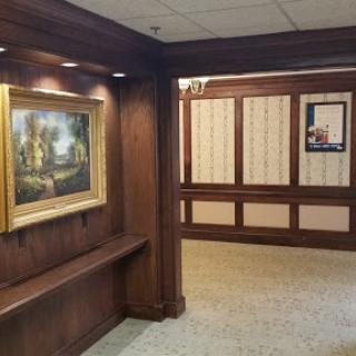 A well-lit hallway featuring an elegant painting and classic wood paneling.