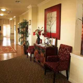 An elegantly decorated hallway featuring artwork, chairs, and a console table.