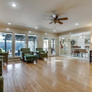 A spacious living room with wood flooring, featuring comfortable seating and large windows.