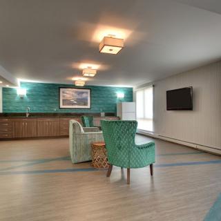 A modern living room with teal accent chairs and a stylish wall design.