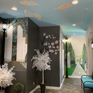 A creatively decorated hallway featuring murals, ceiling art, and decorative trees.