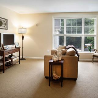 A cozy living room with a sofa, television, and large window.
