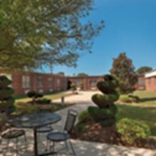 A peaceful outdoor patio with furniture and a garden path leading to a brick building.