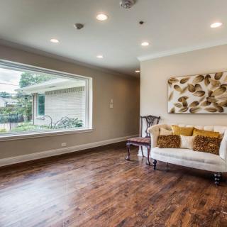 A modern living room featuring hardwood floors, a large window, and comfortable seating.