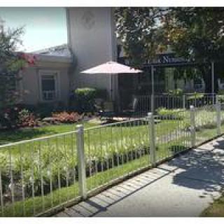 A quaint garden with a fence and patio umbrella adjacent to a building.