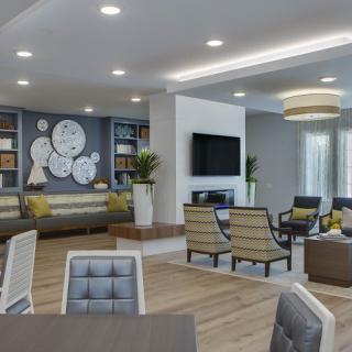 A modern living room with contemporary design featuring a seating area, decorative clocks, bookshelves, and a television.