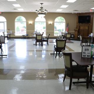 A spacious and well-lit dining area featuring tables and chairs, suitable for gatherings or meals.