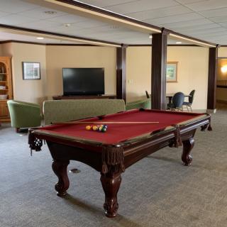 A spacious game room featuring a pool table and a cozy seating area with a television.