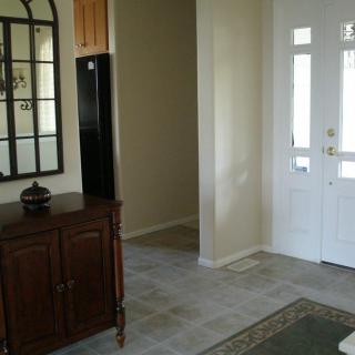 A well-lit entrance hall with a mirror and wooden cabinet.