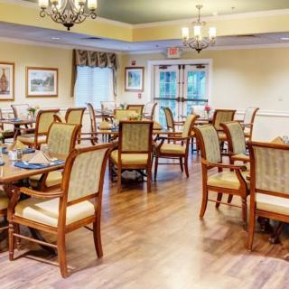 A well-lit dining room with wooden furniture and chandeliers.
