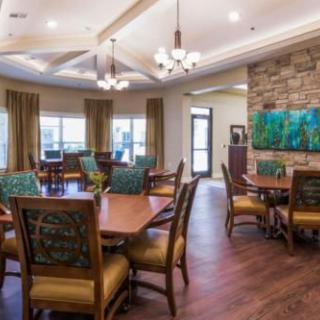 A well-decorated dining room with wooden tables and chairs, featuring elegant lighting and wall decor.