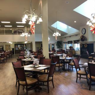 A spacious restaurant dining area with tables and chairs set up, featuring elegant lighting fixtures.