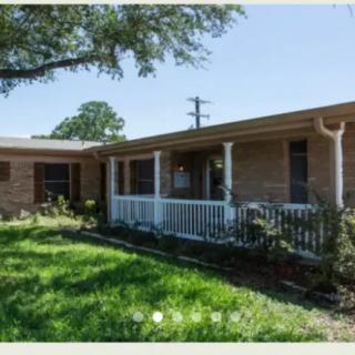 A single-story brick house with a front porch and grassy yard.