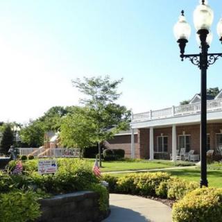 A serene garden area with a pathway and classic lamp posts alongside a building.