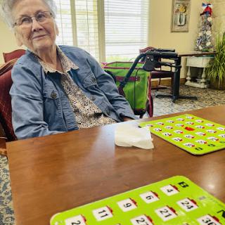 An elderly woman enjoying a game at a communal table.