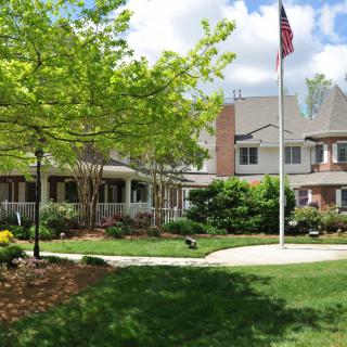 A peaceful building surrounded by a well-maintained garden and a flagpole on a sunny day.
