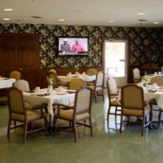 A neatly arranged dining room with tables and chairs, featuring a television on the wall.