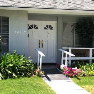 A welcoming house entrance with a garden and flowers.