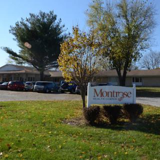 A welcoming sign for Montage surrounded by trees and a parking lot.