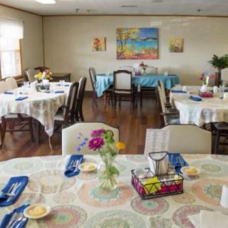 A neatly arranged dining room with several tables set for a meal, adorned with flowers and colorful decor.