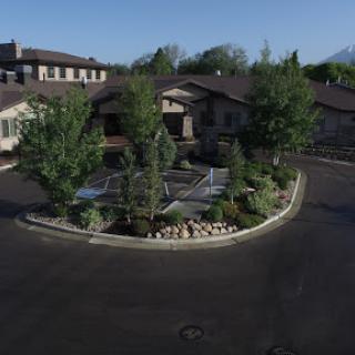 Aerial view of a well-landscaped building with trees and a circular garden.
