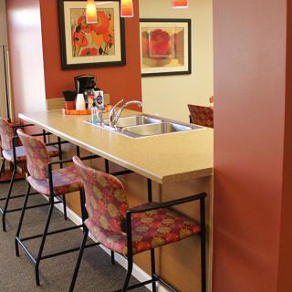 A cozy kitchen area with a long counter, bar stools, and warm pendant lighting.