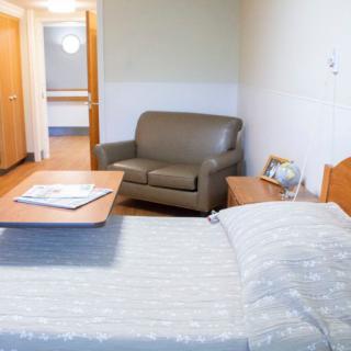 A hospital room featuring a bed, a couch, and a small table.