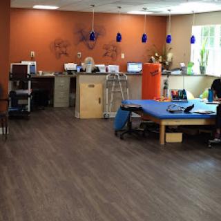 A spacious therapy room featuring workstations and a blue treatment table, designed for rehabilitation.