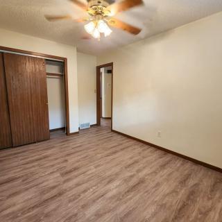 An empty room featuring a wooden floor, ceiling fan, and built-in closet.
