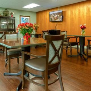 A dining area with tables and chairs, decorated with vases of flowers and a television mounted on the wall.