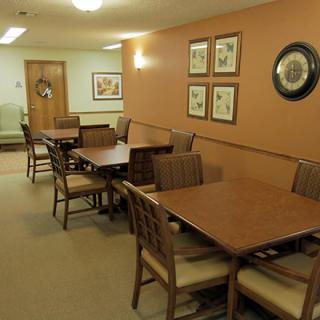 A cozy dining area with wooden tables and chairs, decorated with wall art and soft lighting.