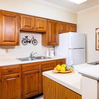 A cozy kitchen featuring wooden cabinets, a white refrigerator, and a countertop with a fruit basket.
