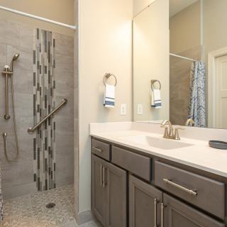 A modern bathroom with a sleek vanity, large mirror, and a walk-in shower.