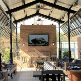 A cozy outdoor patio with comfortable seating and a television mounted on a brick wall.