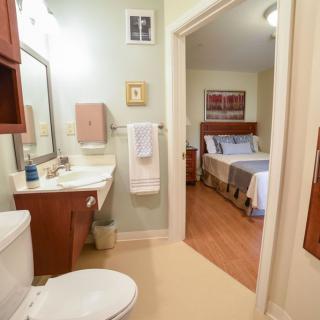 View from a bathroom into an adjacent bedroom, featuring a neat and cozy interior.