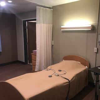 A simple hospital patient room featuring a bed and medical equipment.