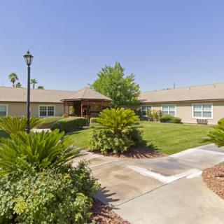 A scenic view of a landscaped garden with a pathway leading to a building on a sunny day.